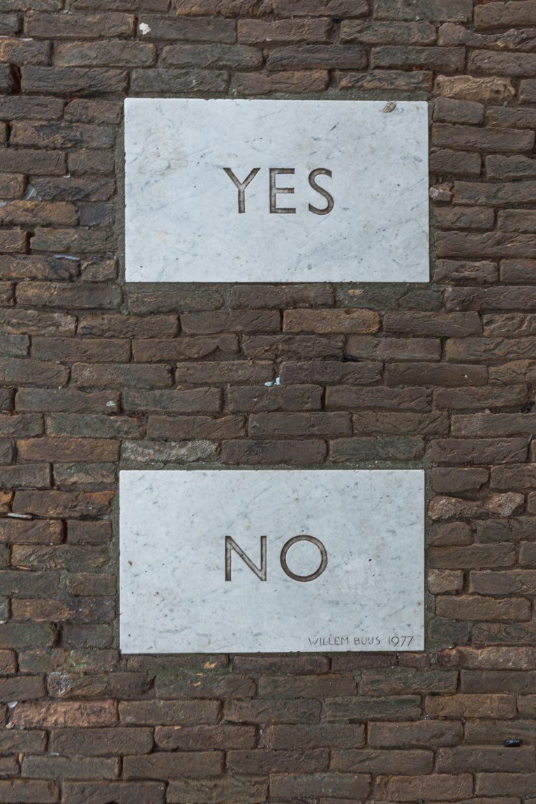 Bachsteinwand mit zwei weissen schildern welche mit Yes und No beschriftet sind
