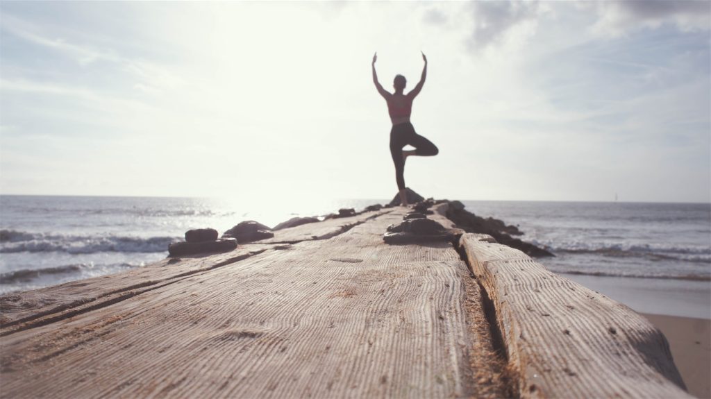 Frau in Yoga-Pose am Strand